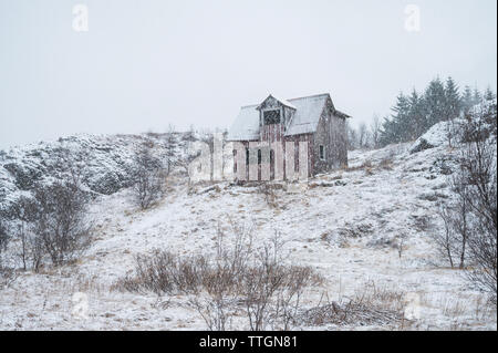 Cabina deserta sulla collina e i fiocchi di neve caduta dal cielo Foto Stock