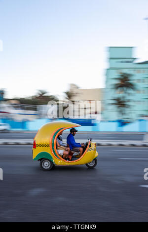 L'Avana, Cuba, 2017: coco taxi guida in strada sul fronte oceano. Il Malecon Foto Stock