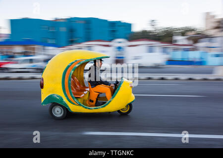 L'Avana, Cuba, 2017: coco taxi guida in strada sul fronte oceano. Il Malecon Foto Stock