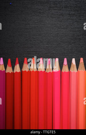 Acquerello matite allineate su una tavola nera. Foto Stock