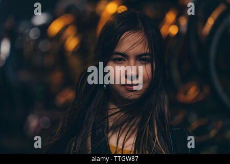 Donna con wet capelli scuri permanente sulla strada di notte mentre rainning Foto Stock