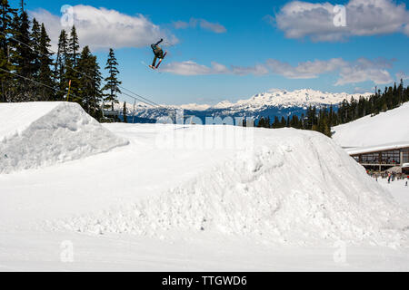 Un uomo colpisce un salto con gli sci nel parco del terreno a Whistler Blackcomb. Foto Stock