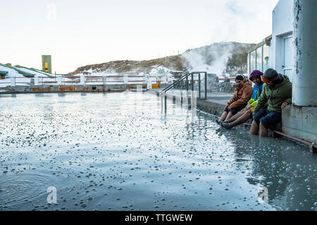 Tre persone immergere i piedi in un bagno di fango dopo una giornata di snowboard Foto Stock