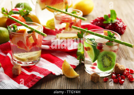 Rinfrescanti cocktail con ghiaccio, menta, i semi di melograno e fette di frutta su sfondo di legno Foto Stock