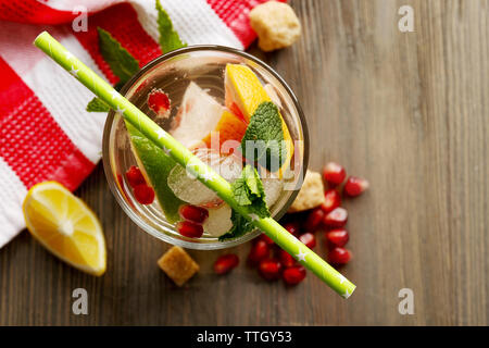 Un cocktail rinfrescante con ghiaccio, menta, i semi di melograno e fette di frutta su sfondo di legno Foto Stock