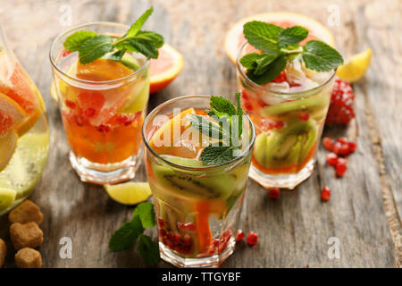 Rinfrescanti cocktail con ghiaccio, menta, i semi di melograno e fette di frutta in legno rustico sfondo Foto Stock