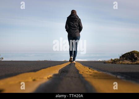 Donna che cammina sulla linea giù la strada sopra le nuvole a Haleakala Parco nazionale sull'isola hawaiana di Maui, STATI UNITI D'AMERICA Foto Stock