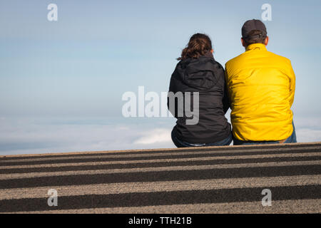 Giovane seduto su un crosswalk sopra le nuvole a Haleakala Parco nazionale sull'isola hawaiana di Maui, STATI UNITI D'AMERICA Foto Stock