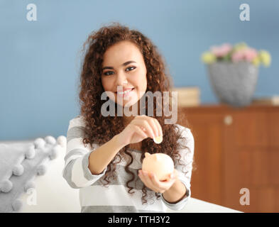 Bella ragazza giovane con salvadanaio sul lettino Foto Stock