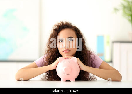 Bella ragazza giovane con salvadanaio in office Foto Stock