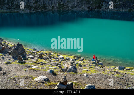 La madre e il figlio in un turchese del lago di montagna delle Alpi in una giornata di sole Foto Stock