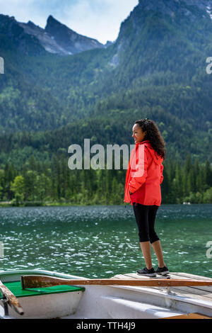 Donna in piedi sul pontile a guardare il paesaggio e sorridente Foto Stock