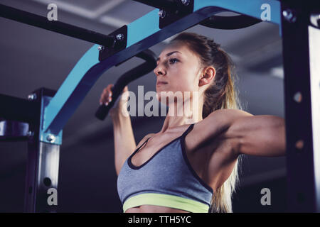 Profilo anteriore della giovane donna facendo chin ups al centro fitness Foto Stock