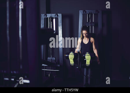 Profilo anteriore della giovane donna facendo gambe allenamento nel centro fitness Foto Stock