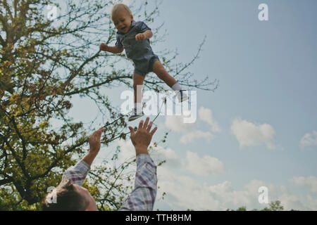 Basso angolo di visione del padre figlio di lancio in aria Foto Stock