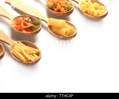 Diversi tipi di pasta secca in cucchiai di legno su sfondo bianco Foto Stock