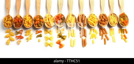 Diversi tipi di pasta secca in cucchiai di legno su sfondo bianco Foto Stock