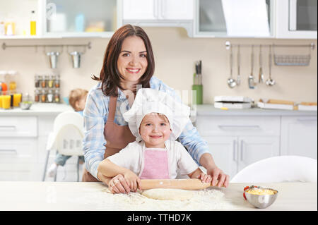 Madre aiutare suo figlio di stendere un impasto, close up Foto Stock