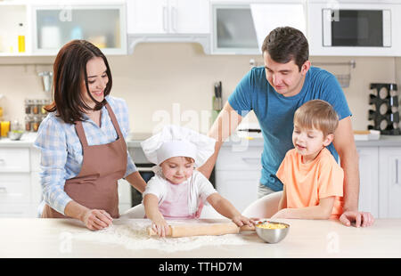 I giovani genitori a guardare la loro figlio a stendere un impasto, close up Foto Stock