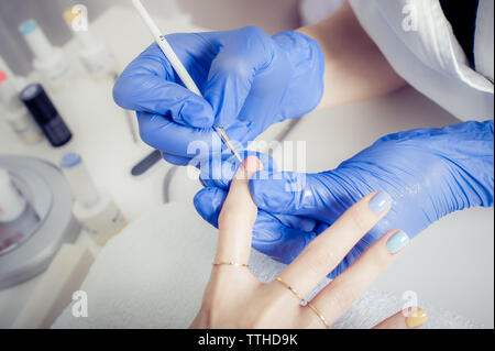 Femmina master manicurist l'applicazione di smalto per unghie in un salone di bellezza. Donna manicure di ricezione Foto Stock