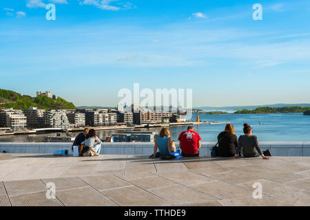 Oslofjord, vista posteriore in estate di gente seduta sul tetto del Teatro dell'Opera di Oslo immobile che guarda verso il porto dell'Oslofjord, Norvegia. Foto Stock