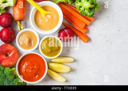 Verdure e frutta purea di bambino (apple, broccoli, carota, prugna) in bianco ciotola con ingredienti. Baby food concept. Foto Stock