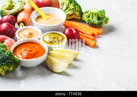 Verdure e frutta purea di bambino (apple, broccoli, carota, prugna) in bianco ciotola con ingredienti. Baby food concept. Foto Stock