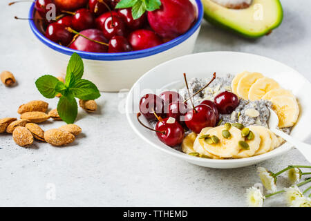 Budino di Chia con banana, ciliegia e i dadi in una piastra bianca. Foto Stock