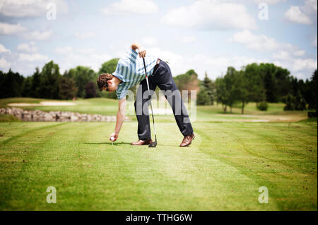 Lunghezza completa dell'uomo mettendo la sfera sul raccordo a T sul campo da golf Foto Stock