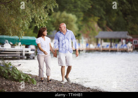 Coppia felice tenendo le mani mentre passeggiate sul lungolago Foto Stock