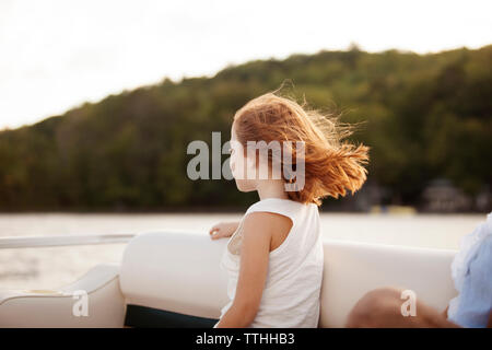 Ragazza guardando a vista mentre si è seduti in barca sul lago Foto Stock