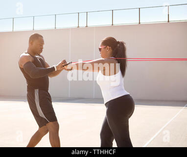 Coach aiutando sportive nel tirare corde sulla giornata di sole Foto Stock