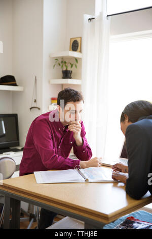 I colleghi avendo discussioni su documenti a tavola in ufficio creativo Foto Stock