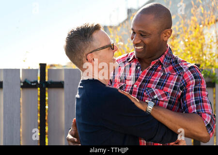 Felice uomini gay abbracciando contro la recinzione Foto Stock