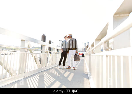 Boyfriends kissing mentre permanente sulla passerella durante la giornata di sole Foto Stock