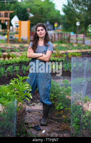 Ritratto di donna fiducioso con le braccia incrociate in piedi presso l'azienda Foto Stock