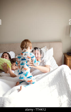 Genitori felici giocando con figli mentre giaceva sul letto Foto Stock