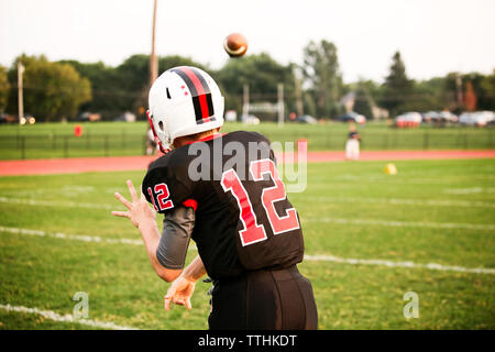 Vista posteriore del giocatore di football americano gettando la sfera sul campo da gioco Foto Stock