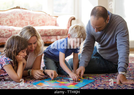 Famiglia puzzle giocando sul pavimento a casa Foto Stock