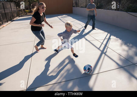 Elevato angolo di visione dei genitori e il figlio che giocano a calcio Foto Stock