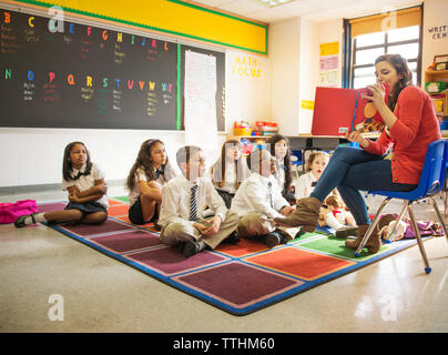 Insegnante che mostra foto libro per gli studenti in aula Foto Stock