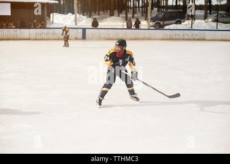 Ragazzo la riproduzione di hockey su ghiaccio durante la giornata di sole Foto Stock