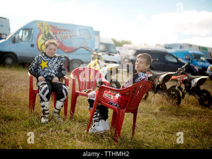 Happy boys seduti su sedie in campo erboso Foto Stock
