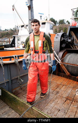 Ritratto di giovane uomo in piedi sulla barca da pesca Foto Stock