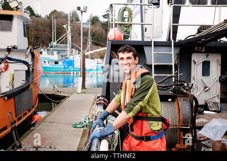 Ritratto di felice pescatore permanente sulla barca da pesca Foto Stock