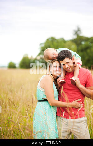 La famiglia felice godendo sul campo erboso contro sky Foto Stock