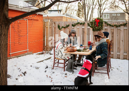 Gli amici sorseggiando sul tavolo e coperta di neve nel cortile Foto Stock