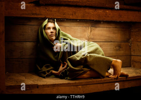 Spaventata donna avvolta in una coperta in sauna Foto Stock