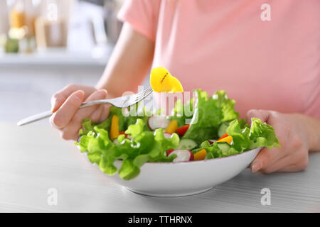 Mano femminile e una ciotola di insalata di verdure sul tavolo di legno closeup Foto Stock