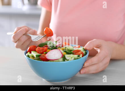 Mano femminile e una ciotola di insalata di verdure sul tavolo di legno closeup Foto Stock